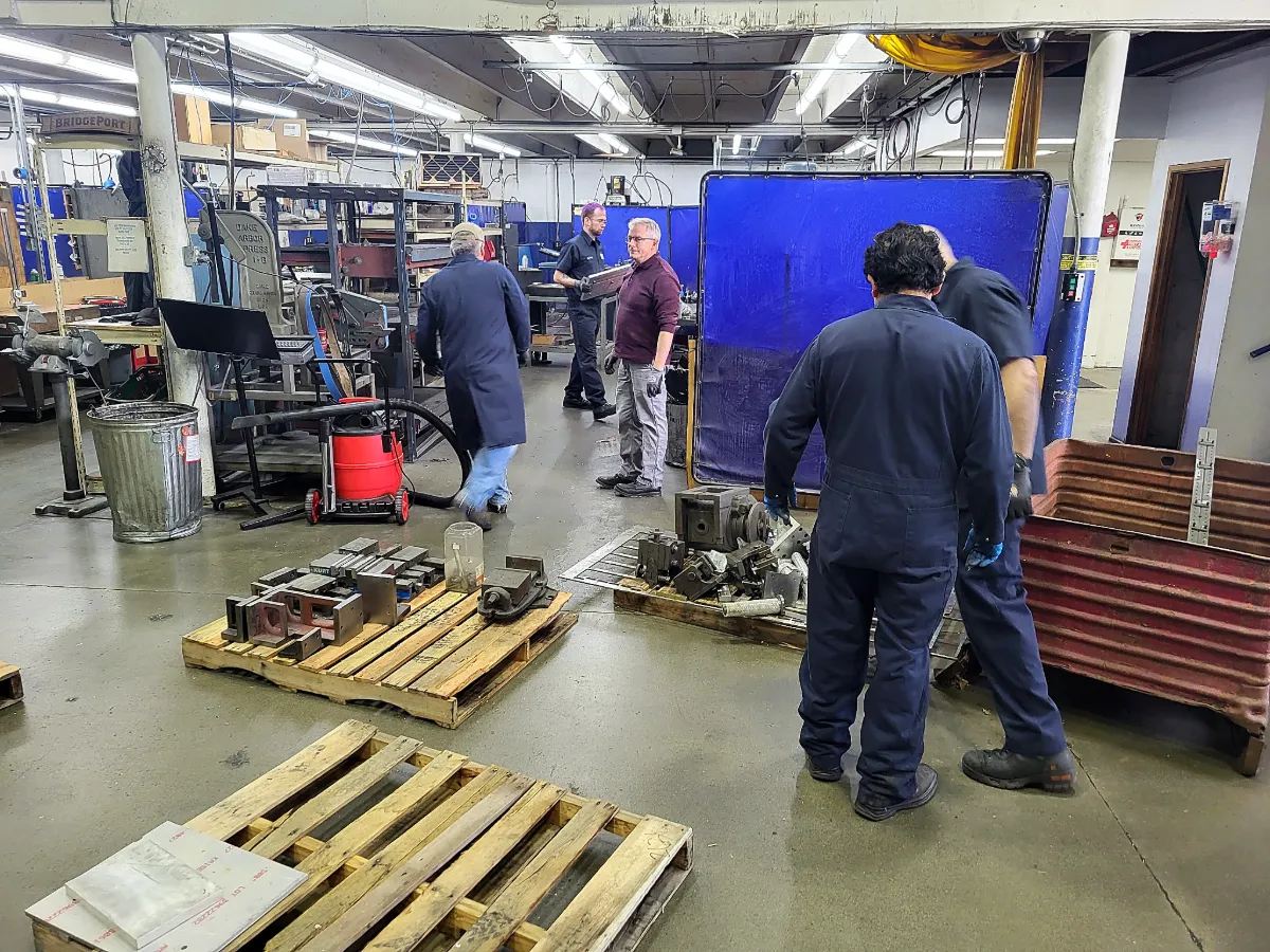 Consultants and operators walking a production floor stacked with pallets of parts