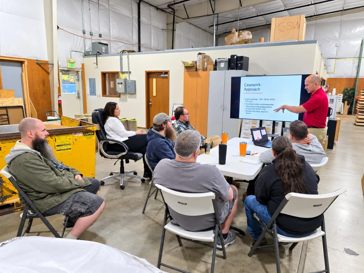 Group seated in a shop-floor training area watching a presentation
