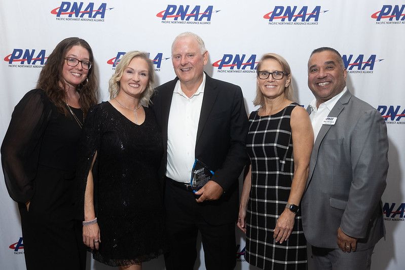 Dan Kocer holding the 2026 PNAA Chair Award with four guests in front of a Pacific Northwest Aerospace Alliance backdrop